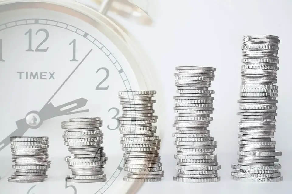 stacks of coins in front of clock