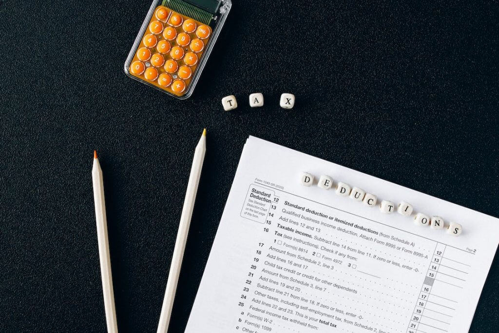 pencils, tax forms and calculator with dice spelling out “tax deductions”