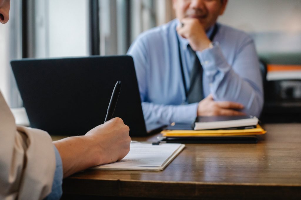 woman writing in front of man and laptop
