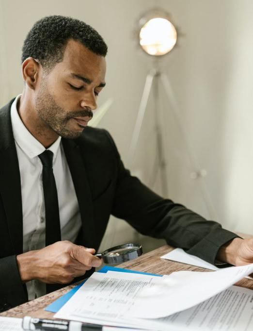 man-reviewing-document-with-magnifying-glass-1024×682